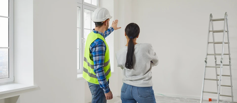 Réparateur professionnel expliquant le futur plan de conception de maison à une jeune femme