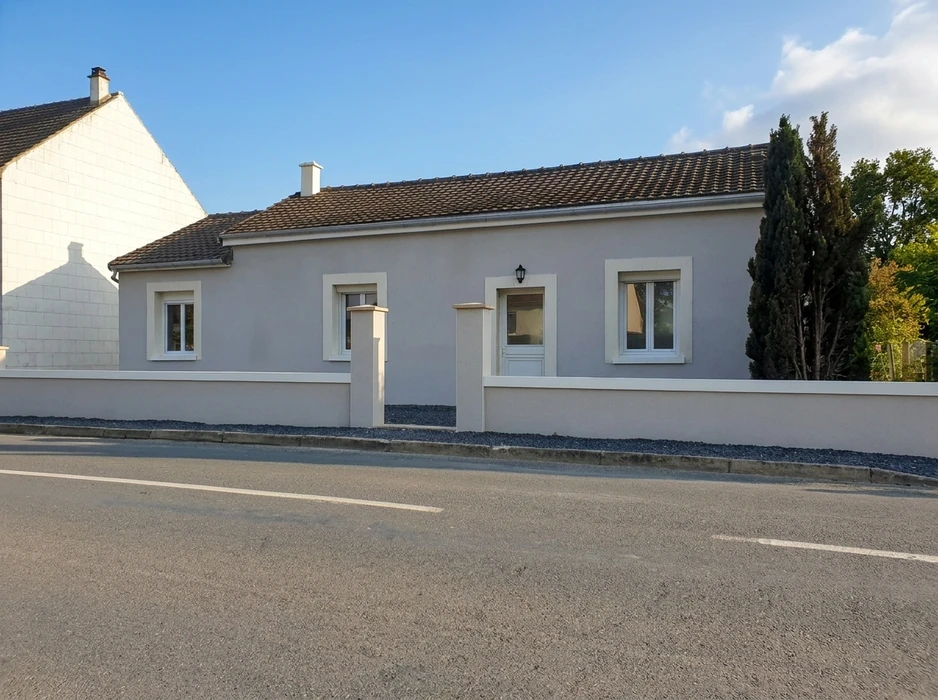 Maison de plain-pied rénovée, façade enduite gris taupe avec encadrements de fenêtres en pierre reconstituée blanche