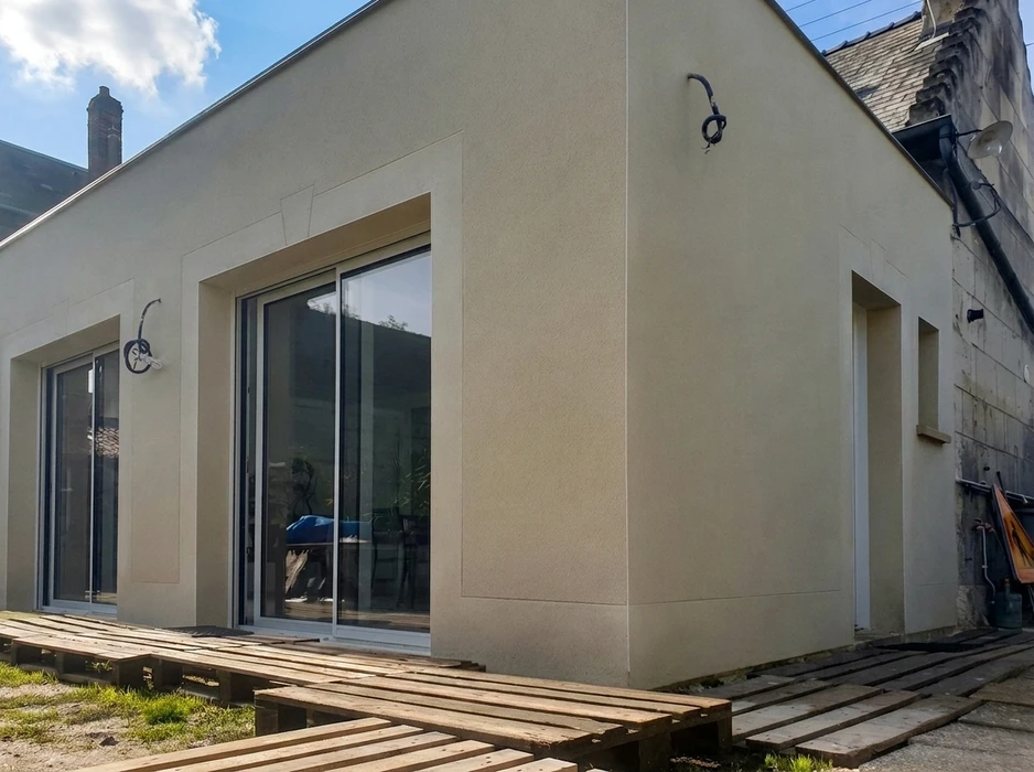 Extension de maison moderne, façade extérieure en enduit minéral ton pierre beige, finition grattée