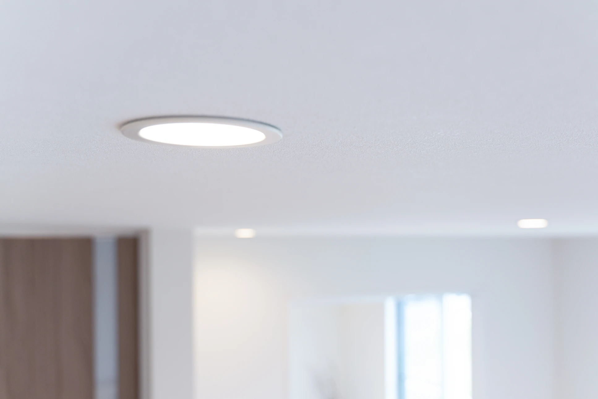 Électricien professionnel en salopette bleue et casque jaune dans cuisine moderne, portant câbles électriques et caisse à outils