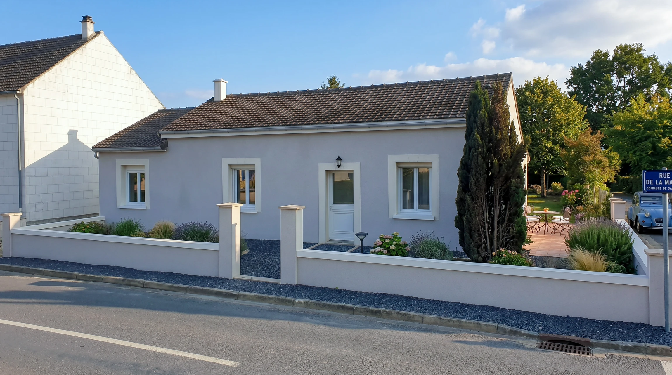 Photographie en façade d'une maison résidentielle dont la façade vient d'être rénovée et ravalée, montrant un enduit frais ou un nettoyage récent de la façade, avec des joints de mortier visibles et une allure soignée mettant en valeur le bâtiment. La scène doit être prise de jour en lumière naturelle, montrant clairement l'amélioration apportée à l'extérieur de la maison.